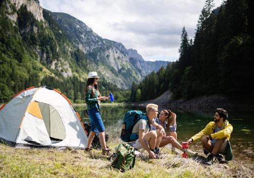 Friends sitting beside a tent in a mountain valley