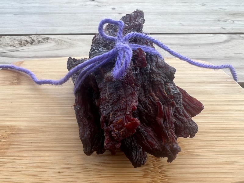 A bundle of jerky strips tied with purple cord