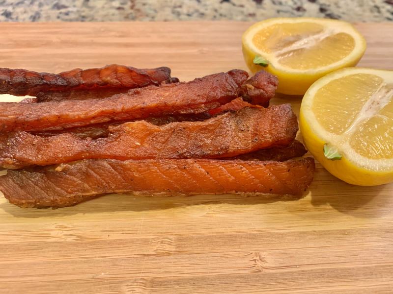 Long salmon jerky strips beside lemon halves