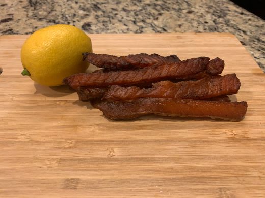Salmon jerky strips stacked beside a whole lemon