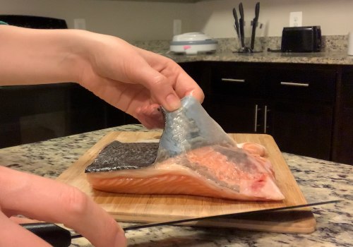 A cook separating salmon skin from the fillet with a knife