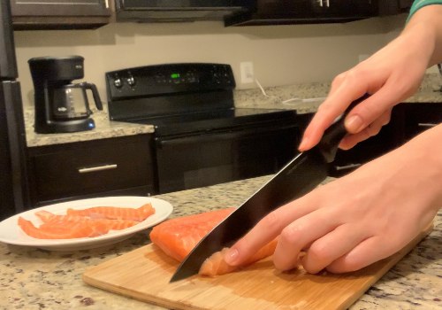 A cook slicing salmon into thin strips