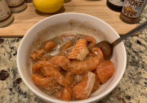 Salmon pieces being stirred through marinade in a bowl