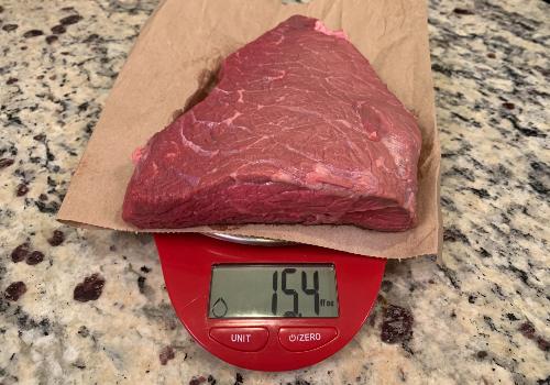 Raw beef on a scale showing 15.4 ounces
