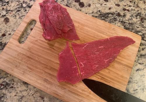 Thin beef slices being cut into smaller pieces