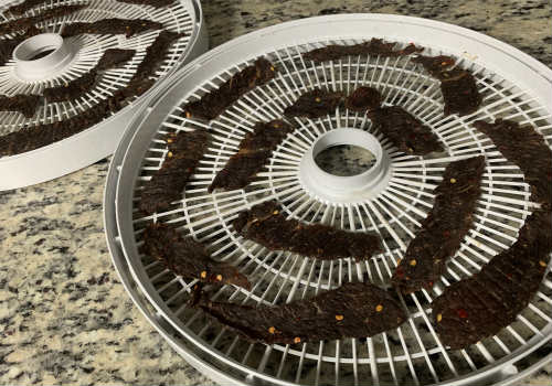Darkened beef jerky on dehydrator trays