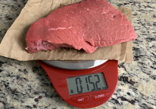 Raw beef on a digital scale set to ounces