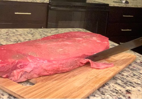 Knife removing a strip of fat from beef