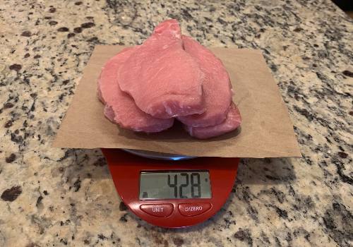 Trimmed pork chops on a scale reading 428 grams