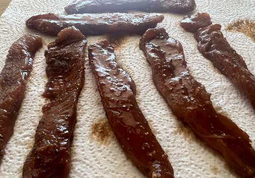 Marinated turkey strips draining on paper towels