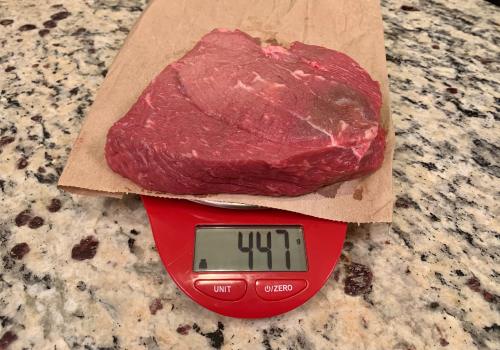 Raw beef on a scale reading 447 grams