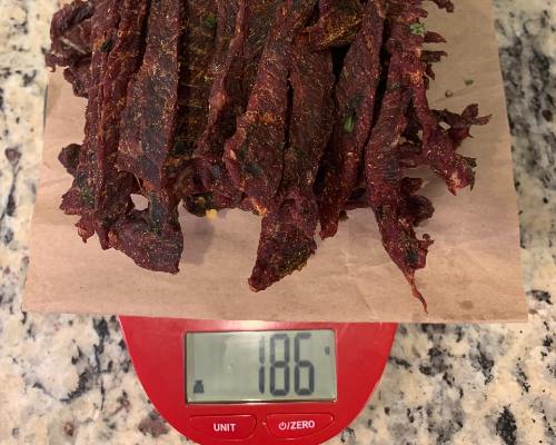 Finished beef jerky on a scale reading 186 grams