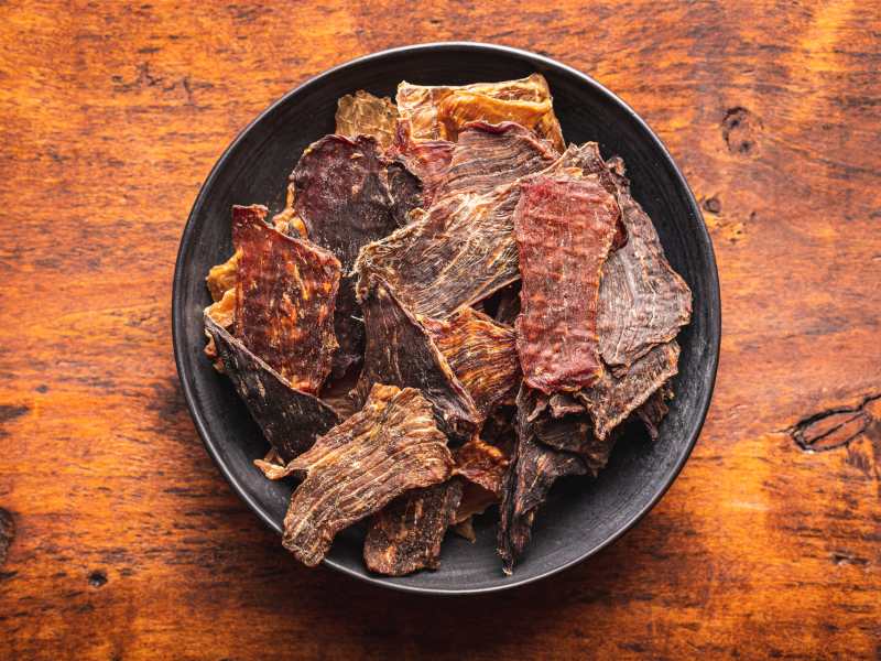 Assorted beef jerky pieces on a black plate