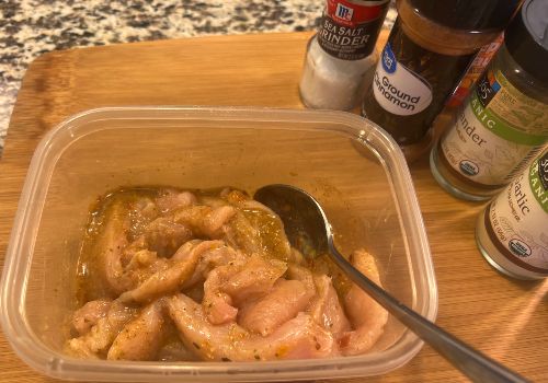 Turkey strips coated with marinade in a plastic container