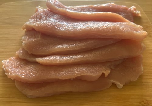 Thin raw turkey cutlets stacked on a board