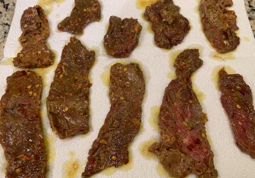 Seasoned beef strips draining on paper towels
