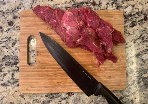 Thin slices of raw beef and a knife on a cutting board