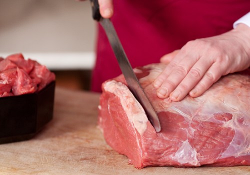 Butcher trimming a large piece of raw meat