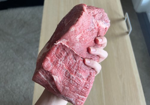 Hand holding a large piece of raw lean beef