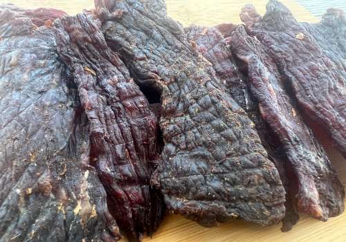 Wide, dark strips of beef jerky piled together